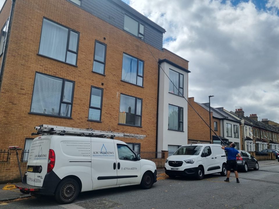 Andrew cleaning the upper windows of a block of flats from the street with a water-fed pole