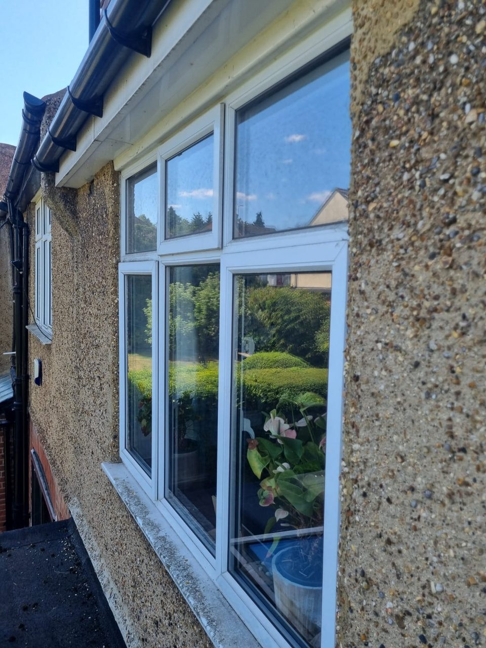 Windows before cleaning, with spotty glass and a dirty sill