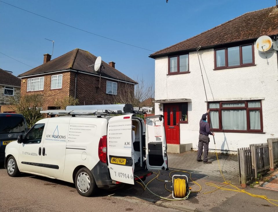 Andrew cleaning the fascias with a water-fed pole, fed from the A.W. Windows van