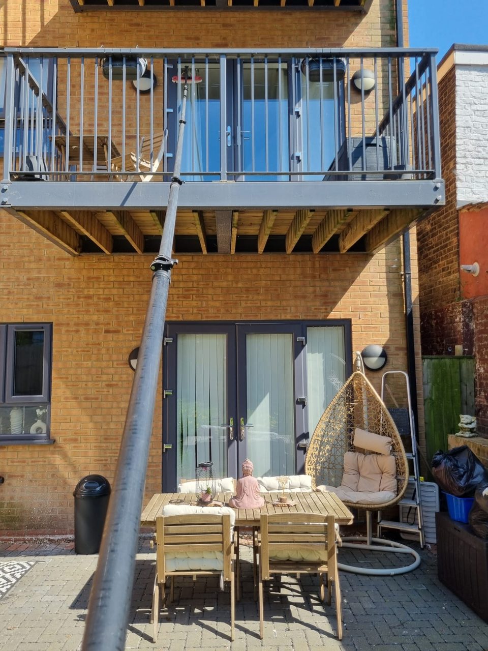 A water-fed pole reaching up to clean the glass doors of a first floor balcony