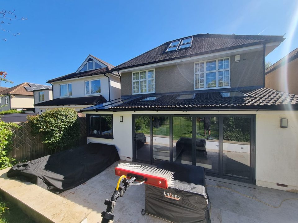 The back of a house with skylights in the roof, a water-fed pole brush in the garden