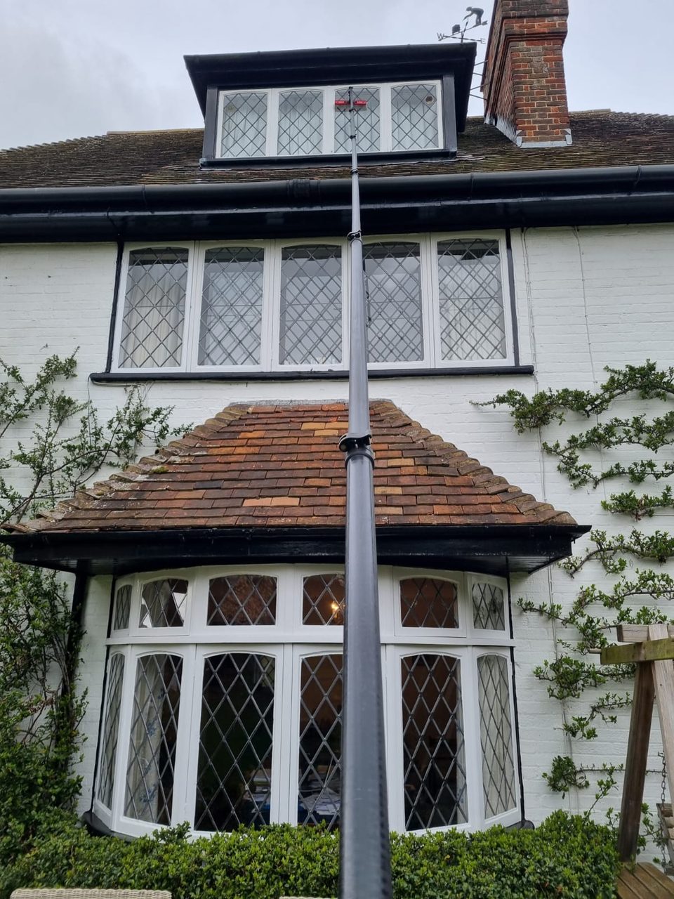 A water-fed pole cleaning the leaded windows of a period home, up to the dormer